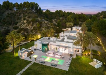 Twilight aerial view of the contemporary estate at 72 Beverly Park, Beverly Hills, with pool, spa and lawn set against the hillside
