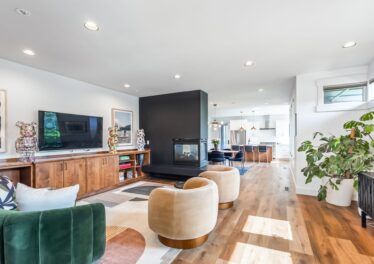 Open-concept living room with a black tile fireplace looking through to the kitchen at 2306 NW Floyd Ln, Bend, OR